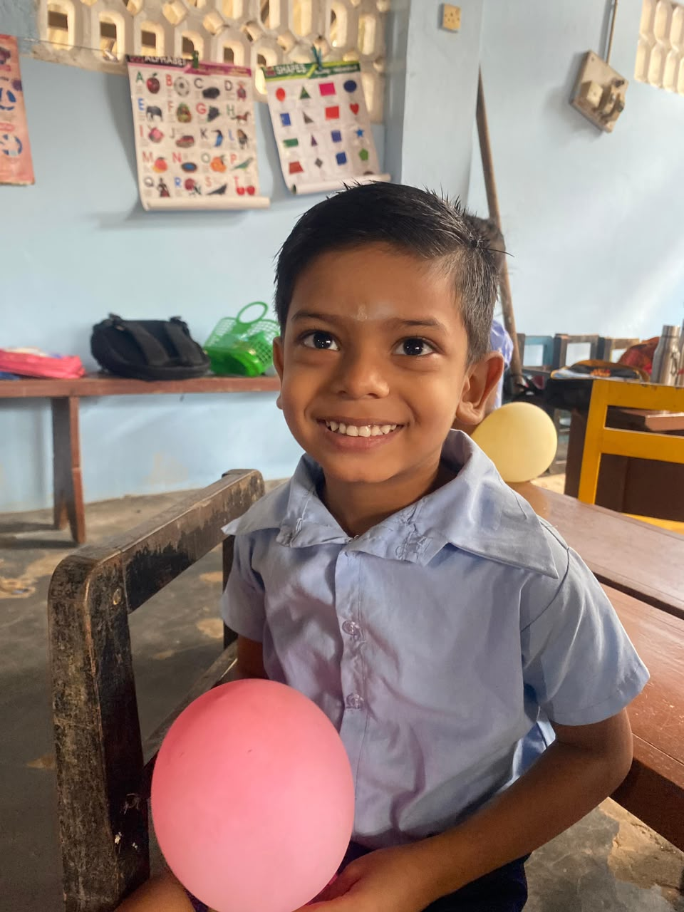 A smiling child holding a balloon during an English Through Play activity