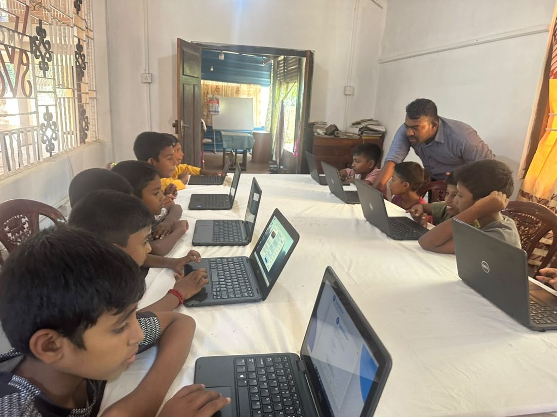 Children learning on laptops with a CPYE instructor